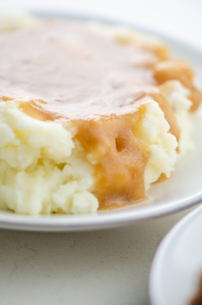 Close up side photo of mashed potatoes with gravy. 