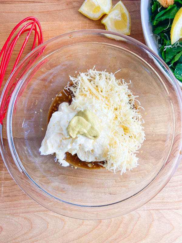 Ingredients for creamy caesar dressing in a glass bowl. 