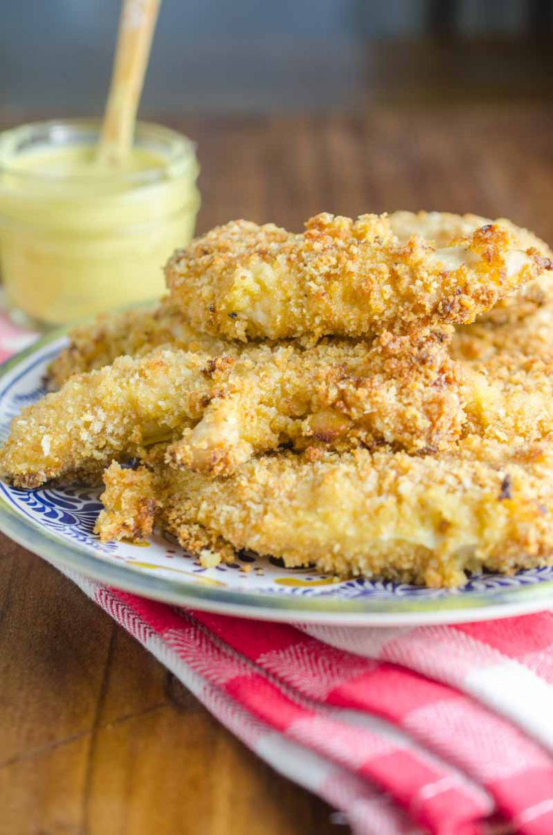 Baked Honey Mustard Chicken Tenders are marinated in honey mustard dressing, dredged in panko and baked until golden. They are a family favorite and perfect for weeknights!