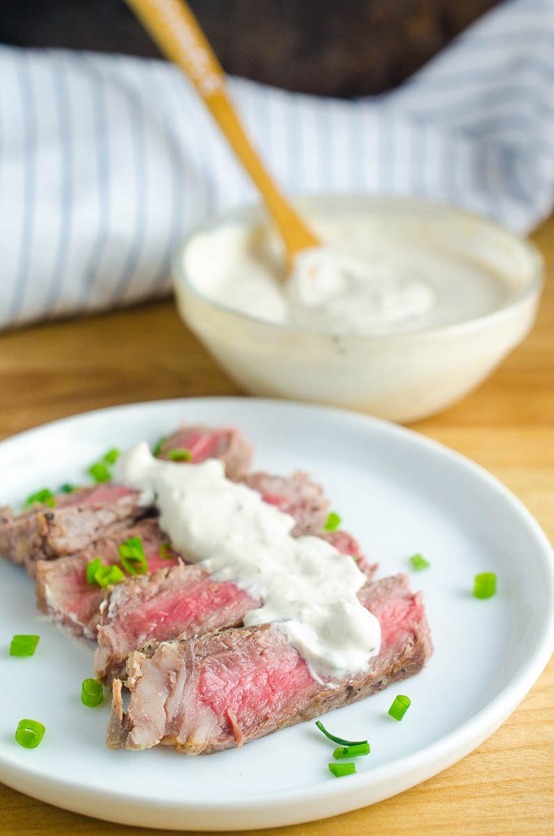 A plate of steak with creamy steak sauce. 