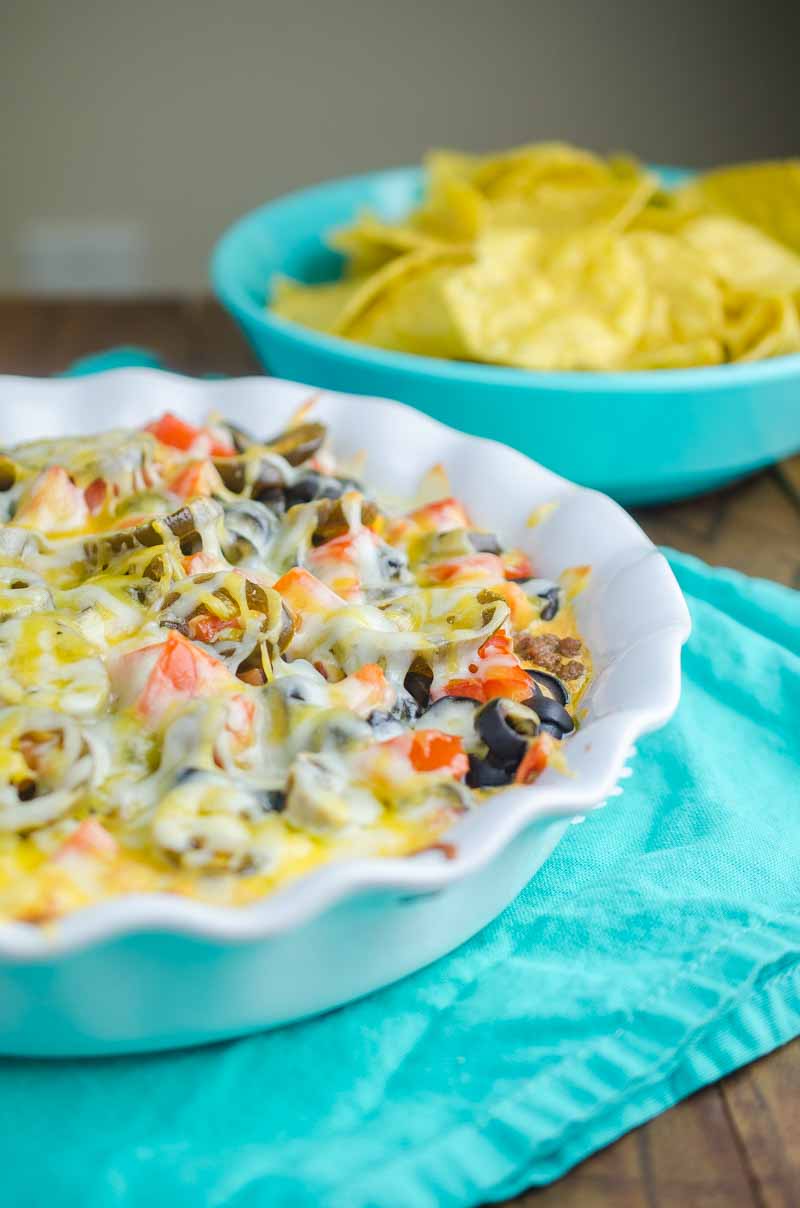 Side angle photo of hot nacho dip in a white dish. 