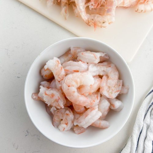 Peeled and deveined shrimp in a white bowl.