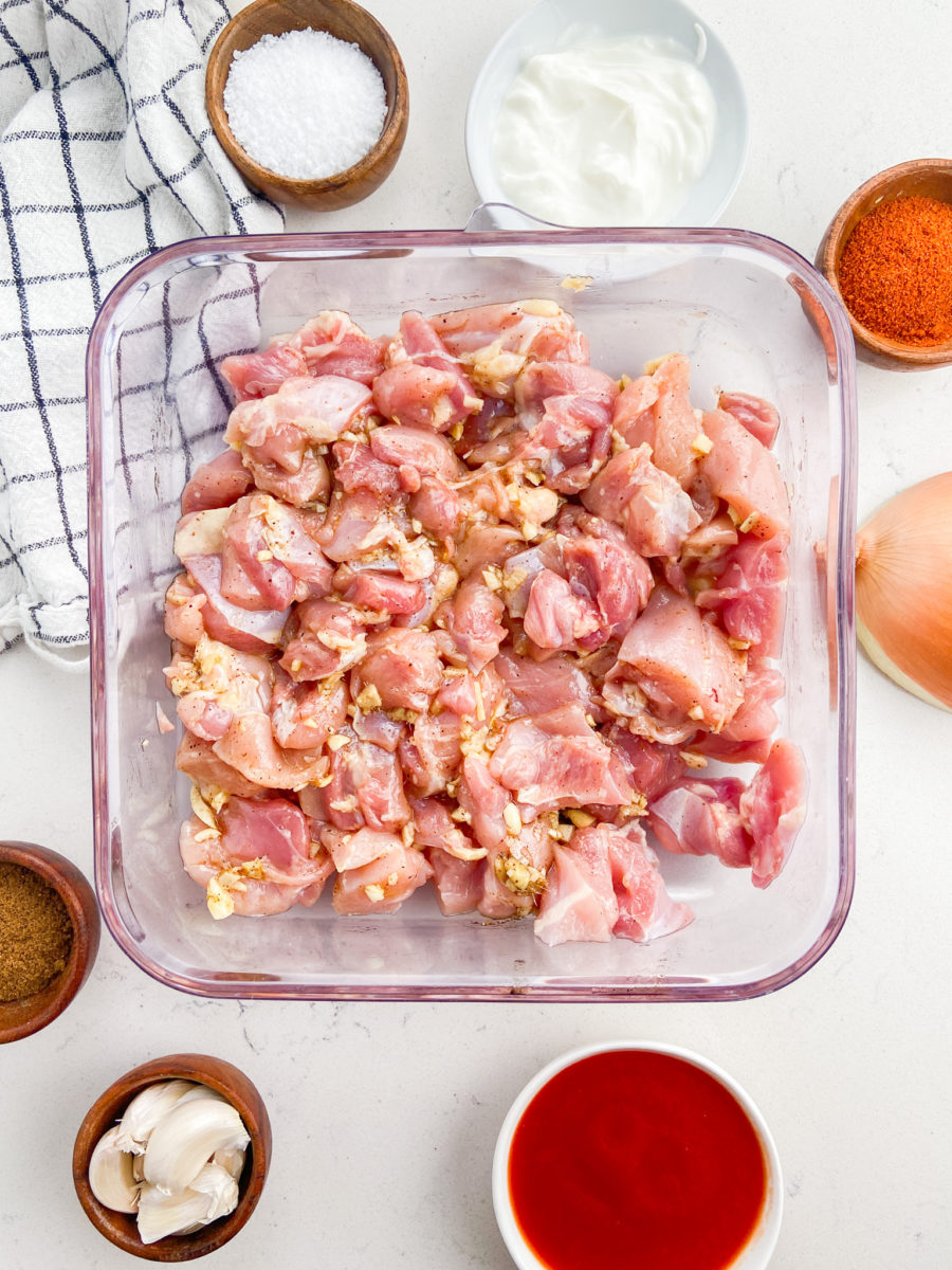 Diced chicken thighs marinating in plastic dish. 