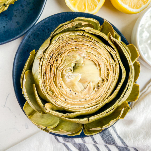 Overhead photo of steamed artichoke with lemons.