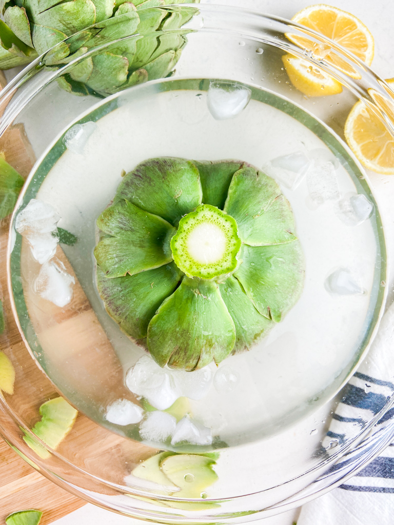 Dipping an artichoke in lemon water to prevent oxidizing. 
