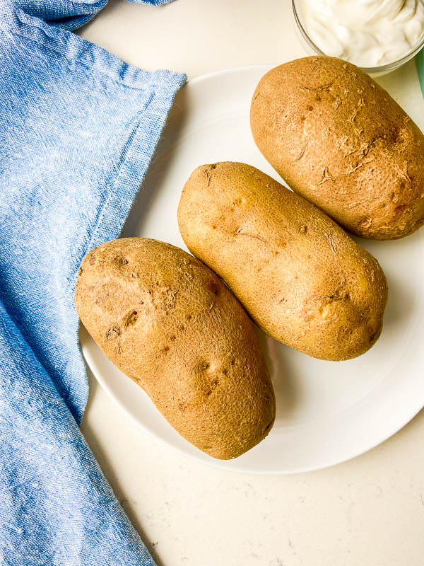 Pressure cooker baked potatoes on a white plate. 