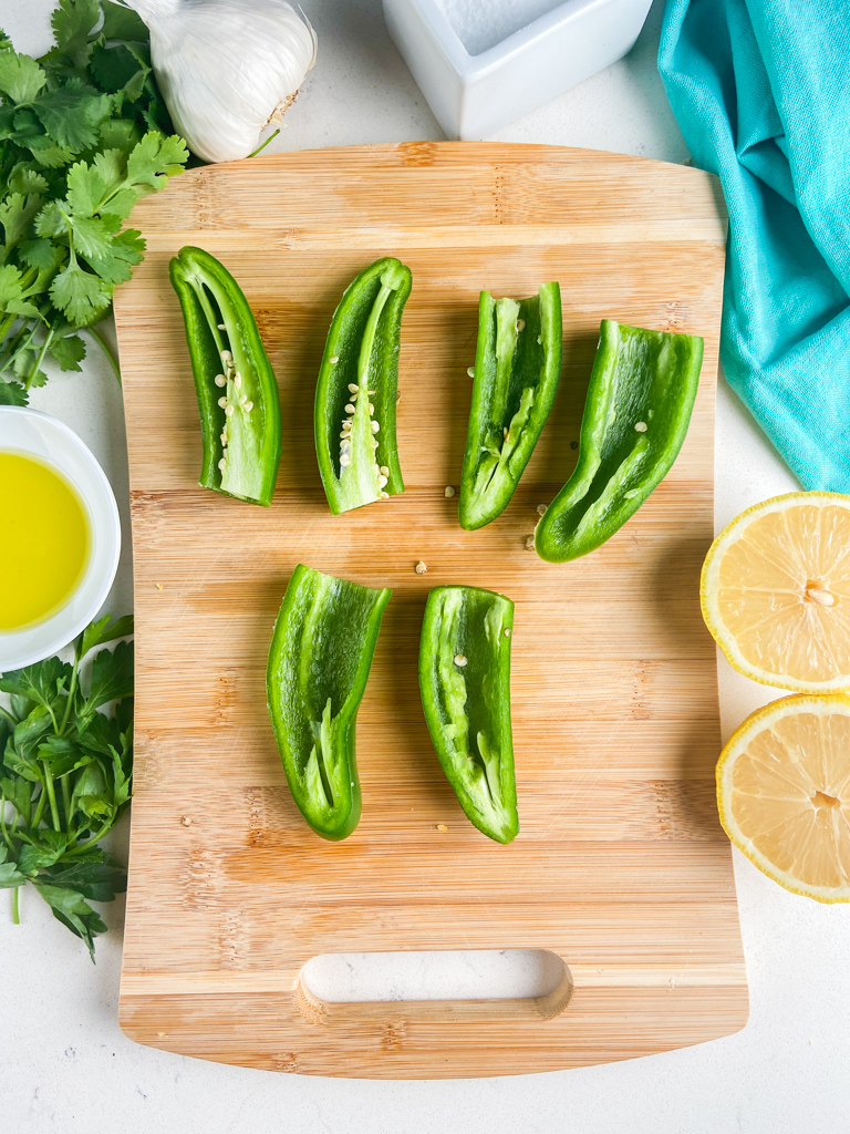 Overhead photo of jalapenos sliced in half on a cutting board. 