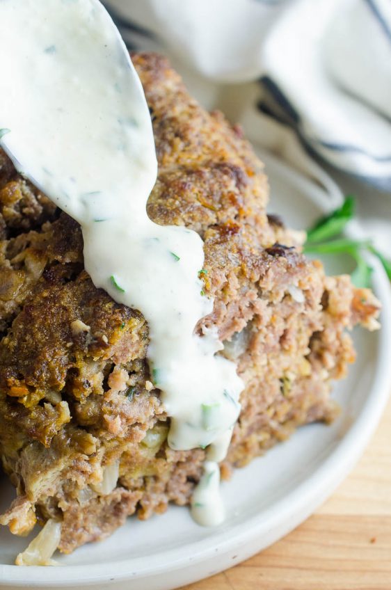 Spooning meatloaf sauce over a slice of meatloaf.