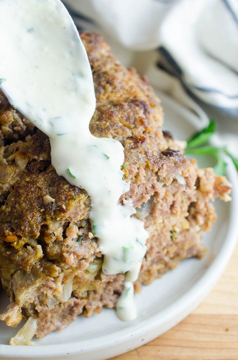 Spooning meatloaf sauce over a slice of meatloaf. 