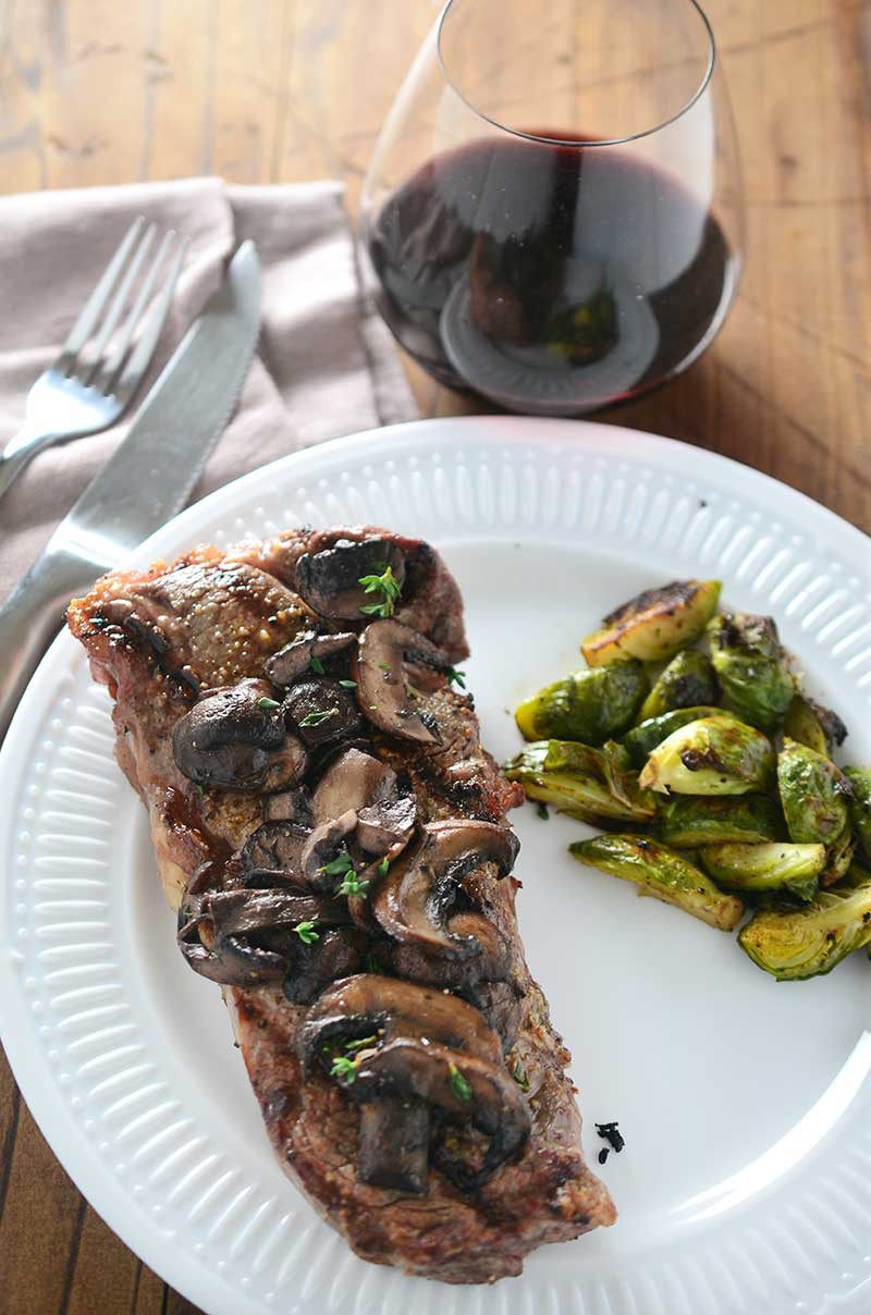 Perfectly grilled New York Strip steak smothered with red wine mushrooms. 