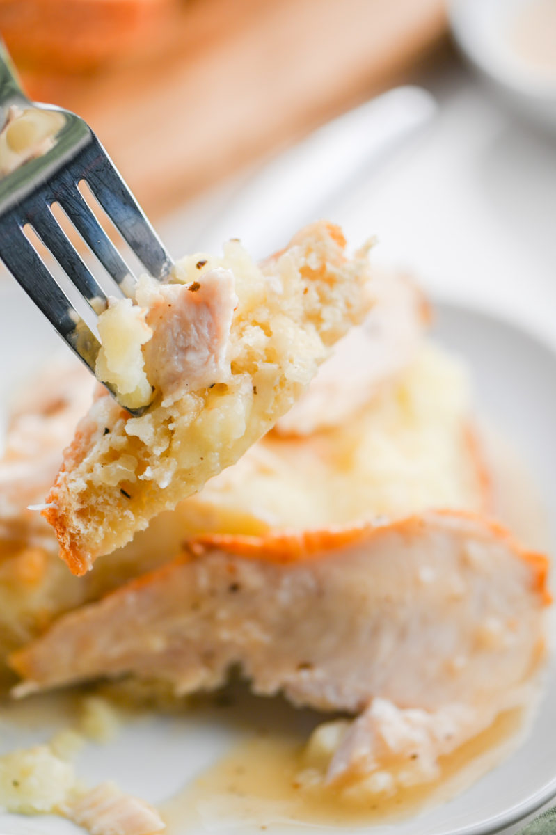A bite of open faced turkey sandwich on fork. 