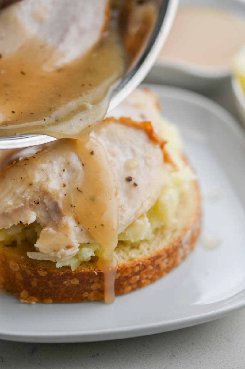 Pouring gravy over turkey sandwich.