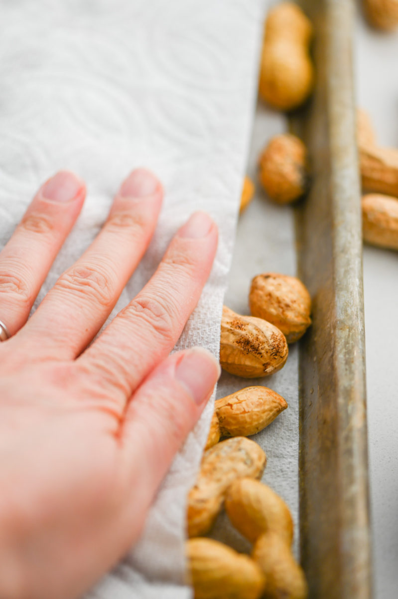 Hand on paper towel patting dry peanuts.  