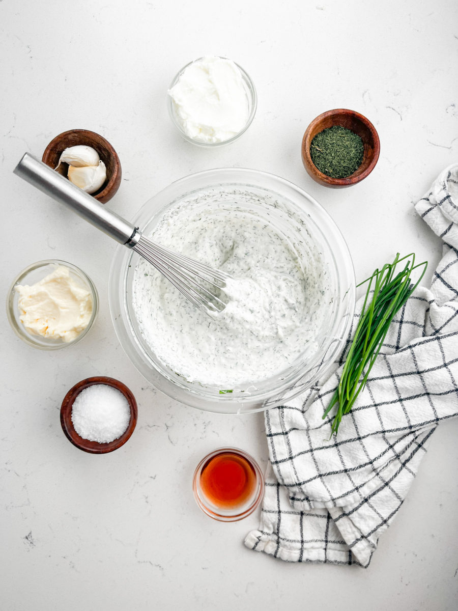 Parmesan ranch dip in glass bowl with a whisk. 