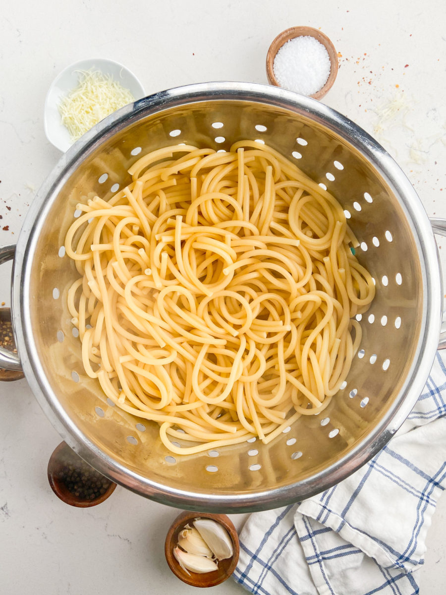 Bucatini pasta in a colander. 