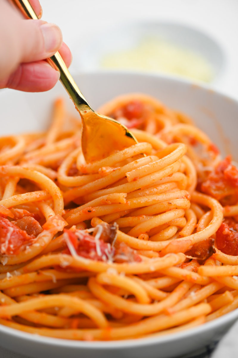 Pasta Amatriciana twirled on gold fork. 