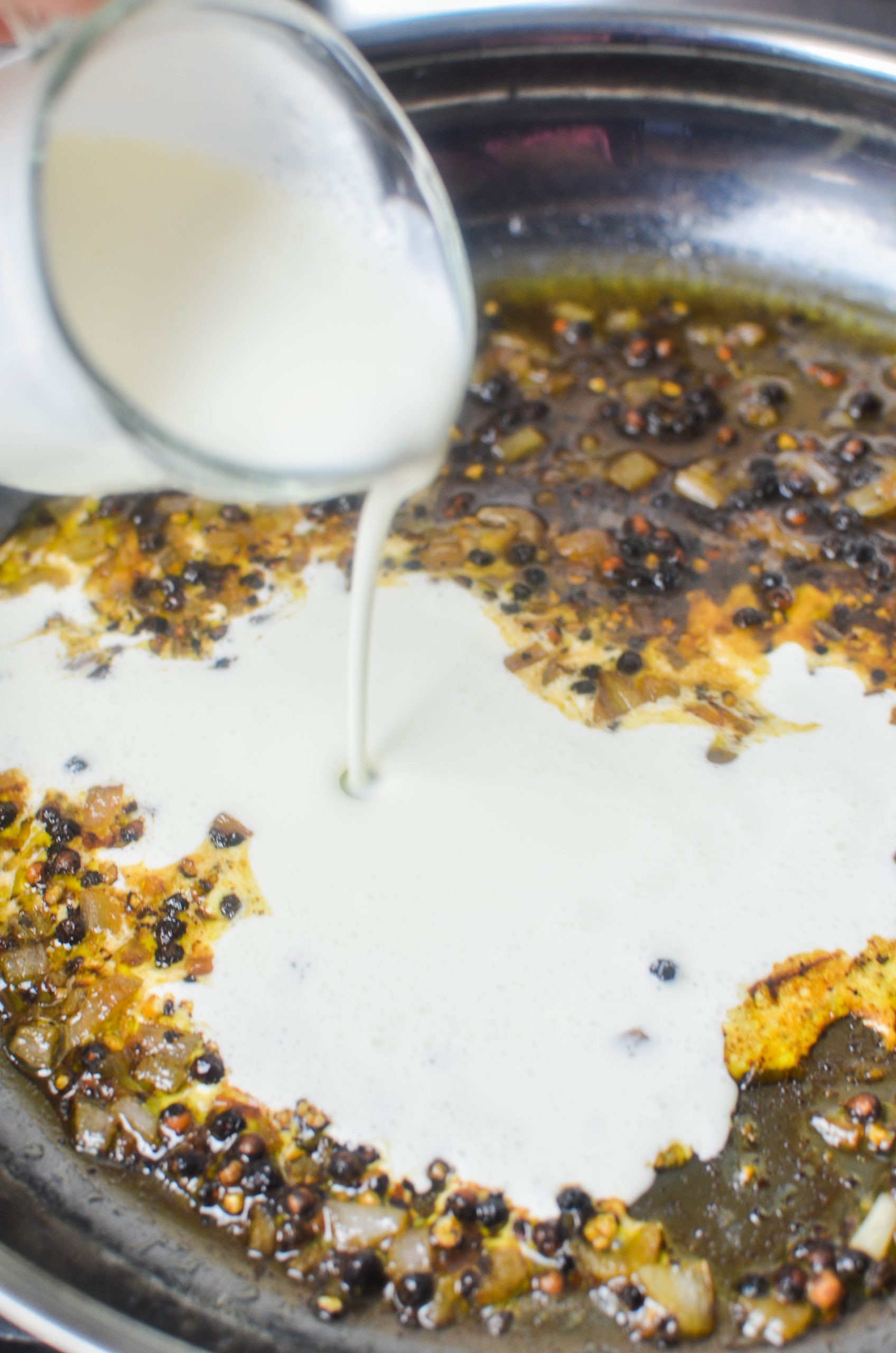 Pouring cream into a skillet.
