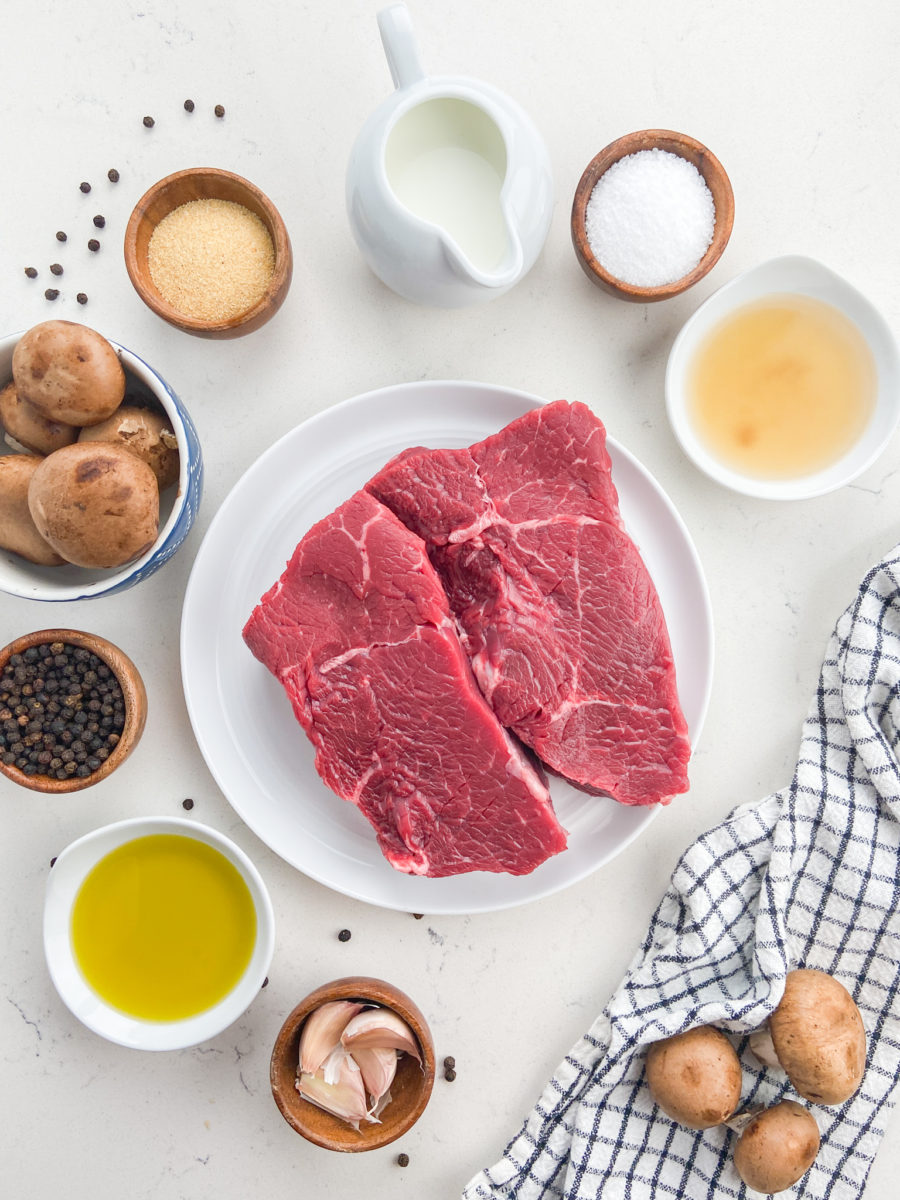 Overhead photo of ingredients needed to make mushroom steak sauce on white background. 