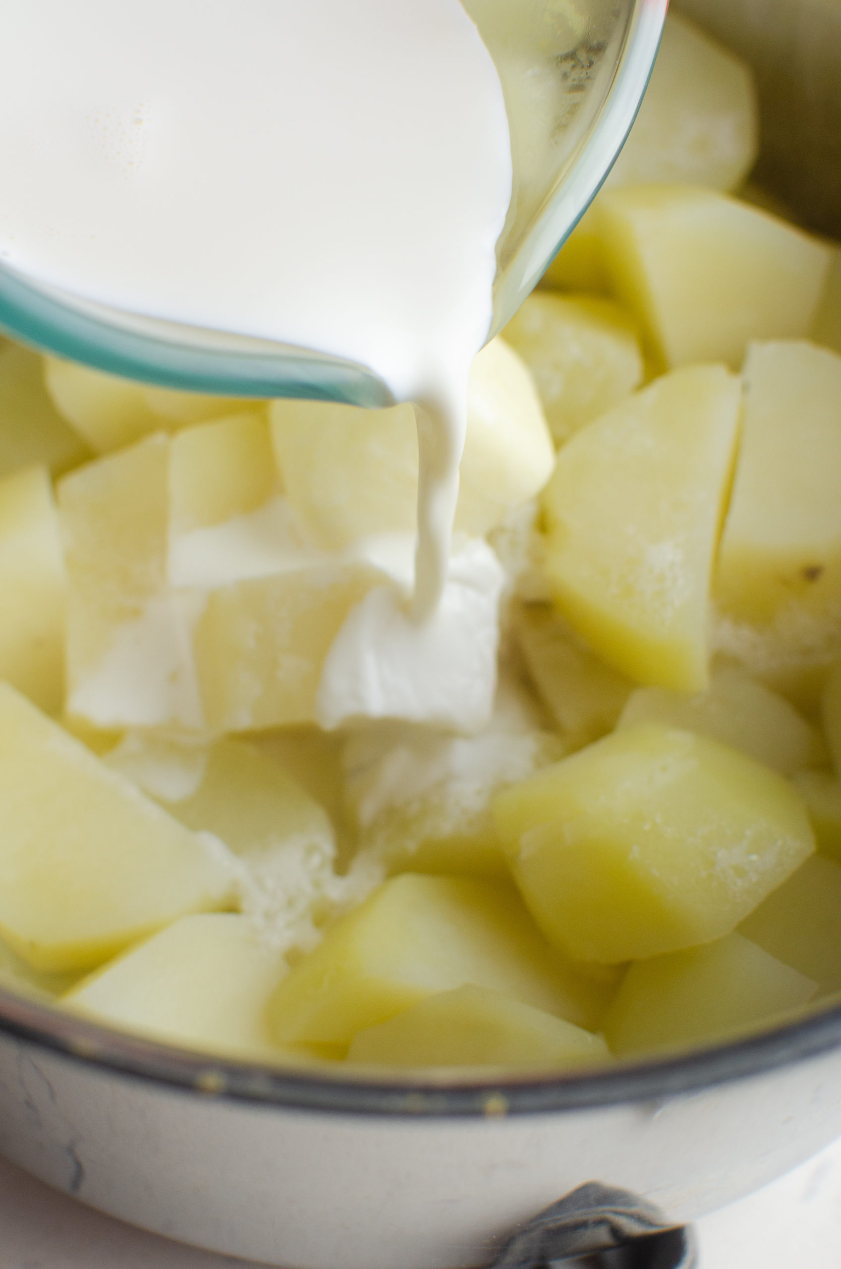 Pouring cream into potatoes.