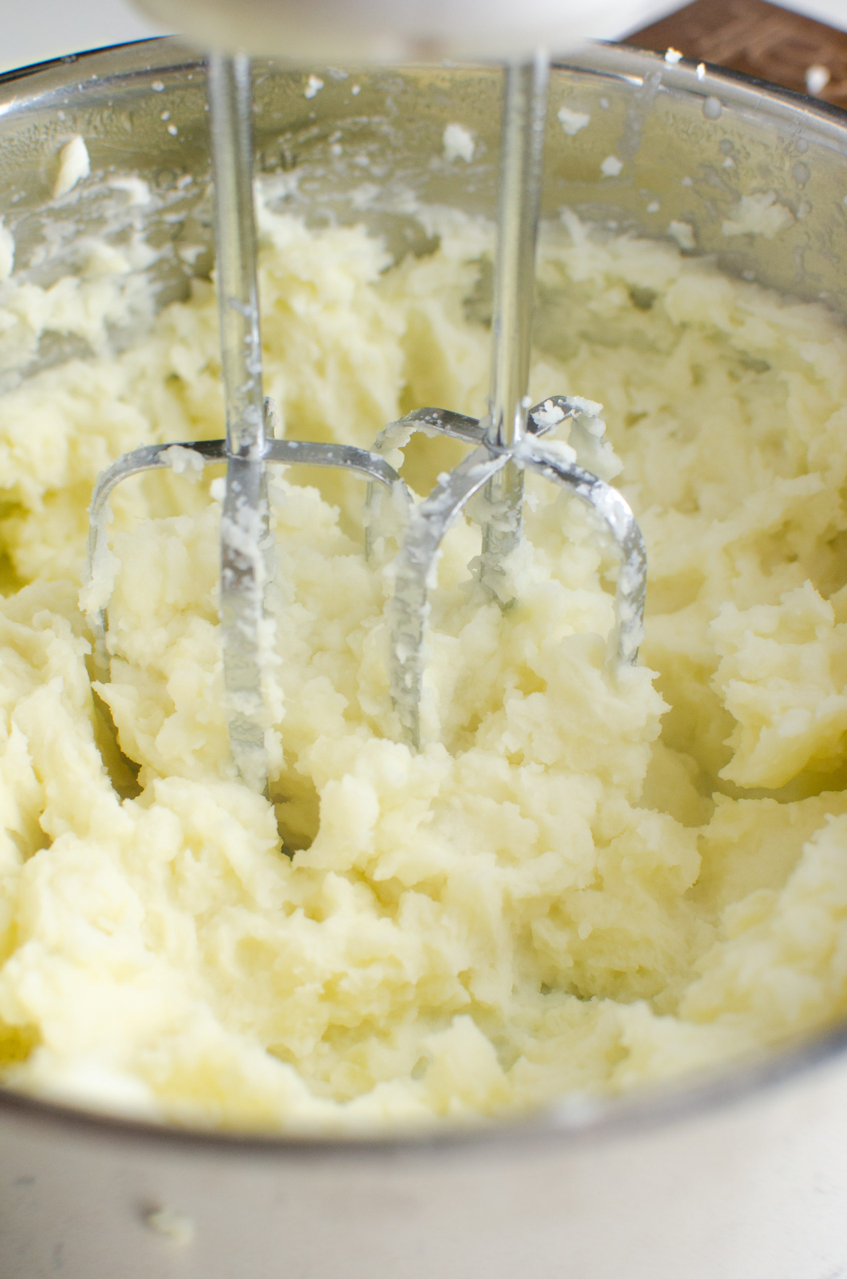 Handheld mixer mixing potatoes. 