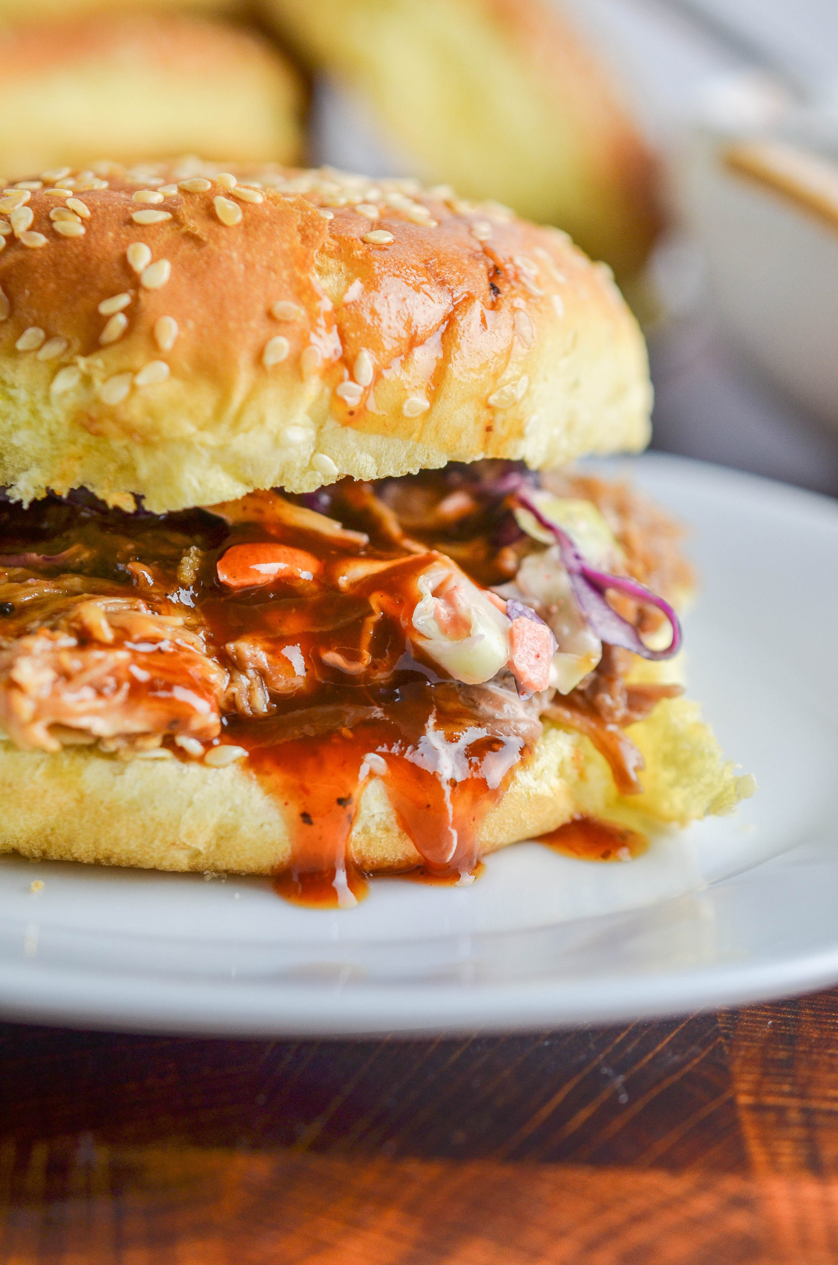 Side angle photo of BBQ Pulled pork sandwich on a white plate. 