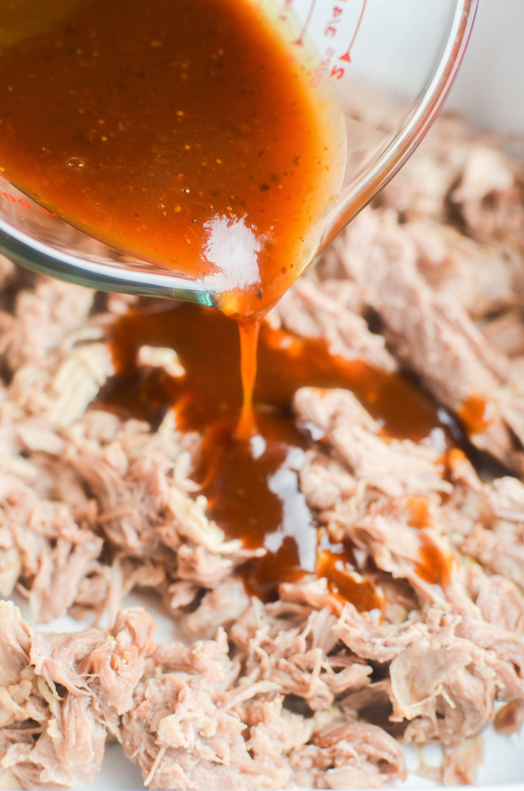 Pouring BBQ Sauce over pulled pork. 