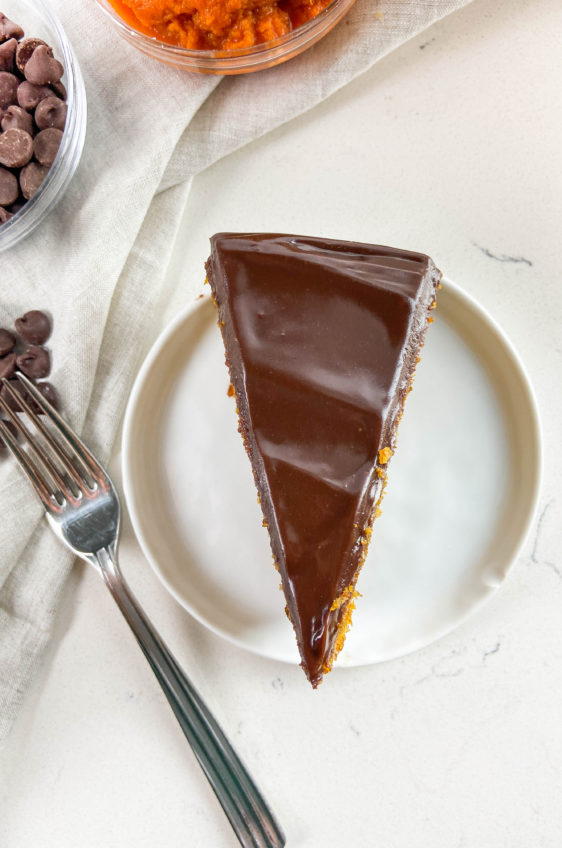 Overhead photo of pumpkin cake with chocolate ganache on white plate.