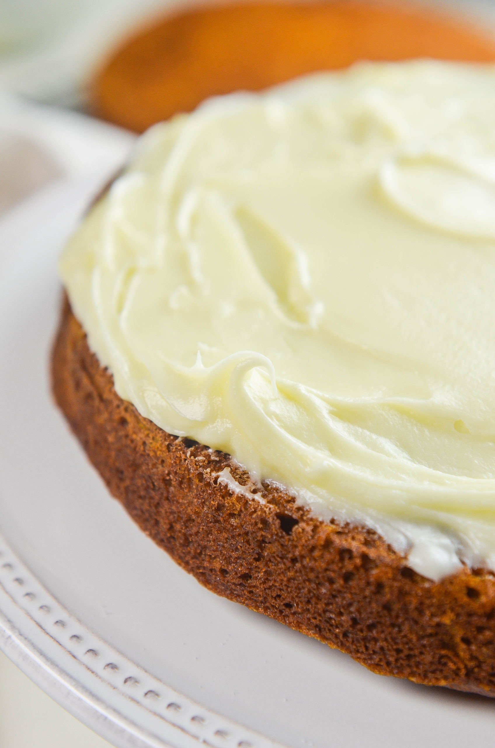 A layer of cream cheese frosting on top of a pumpkin cake. 