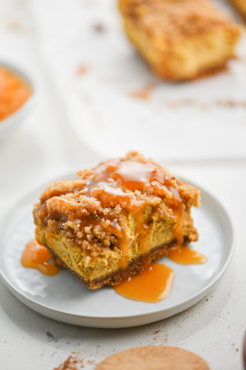 Pumpkin Cheesecake Bar on white plate with caramel sauce. 