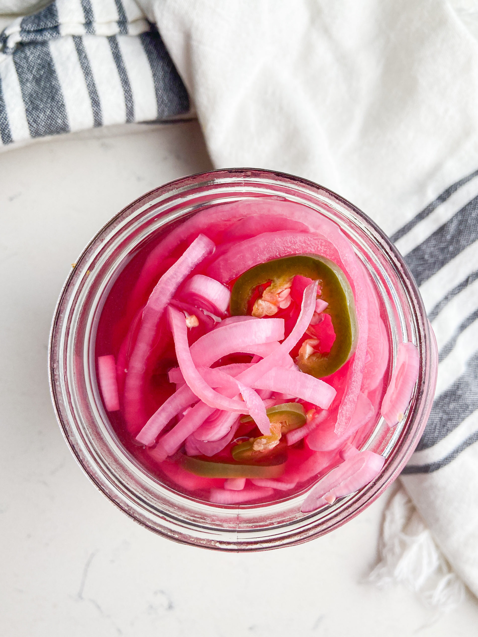 Overhead photo of pickled red onions in a glass jar. 