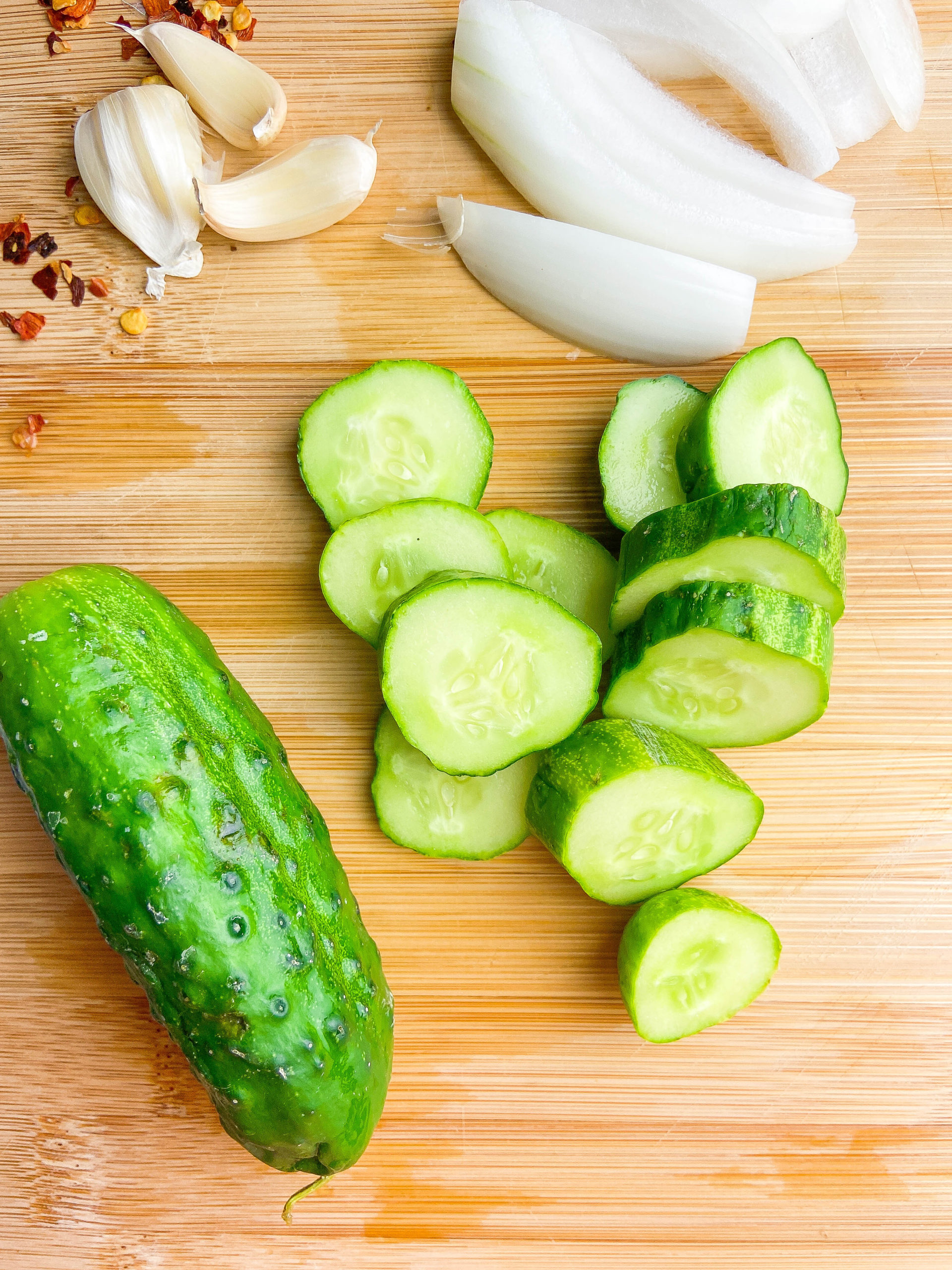 Cucumbers cut into rounds on a wooden cutting board. 