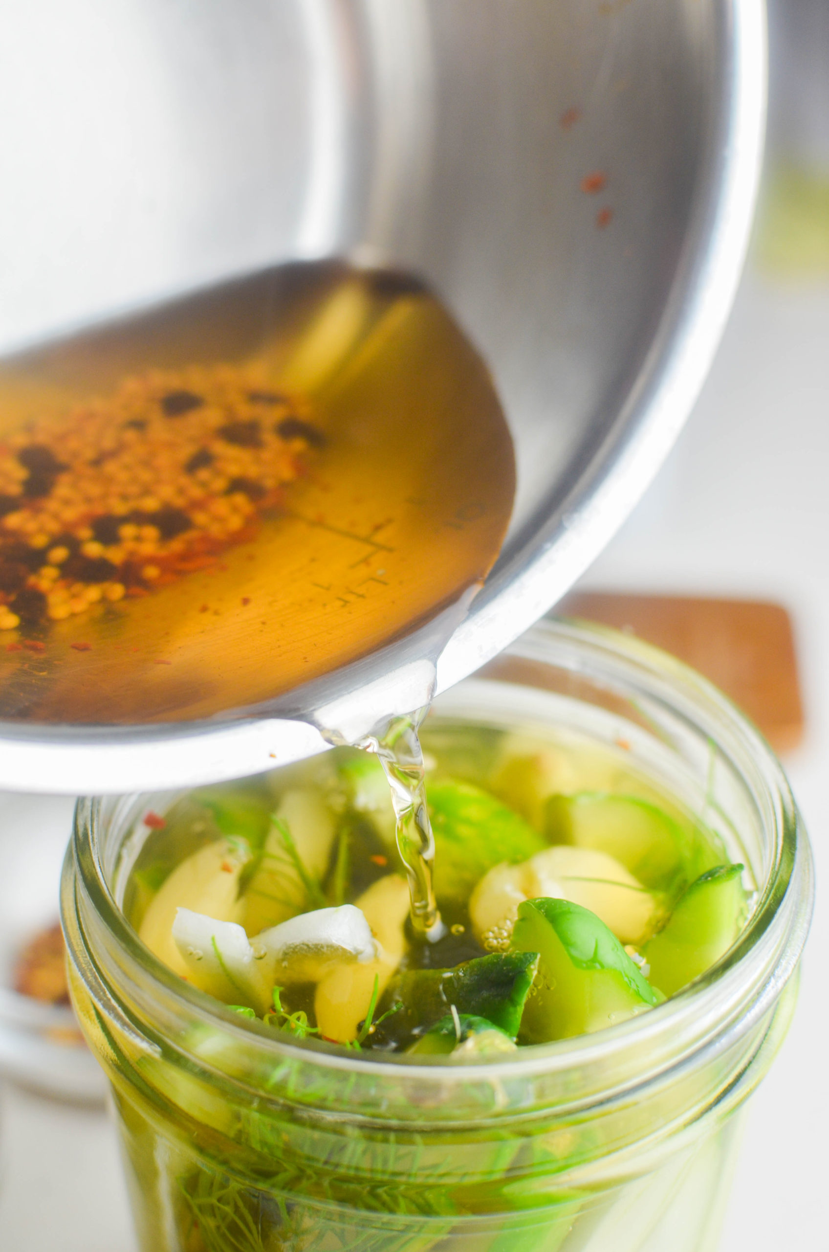 Pouring brine over the vegetables in a glass jar