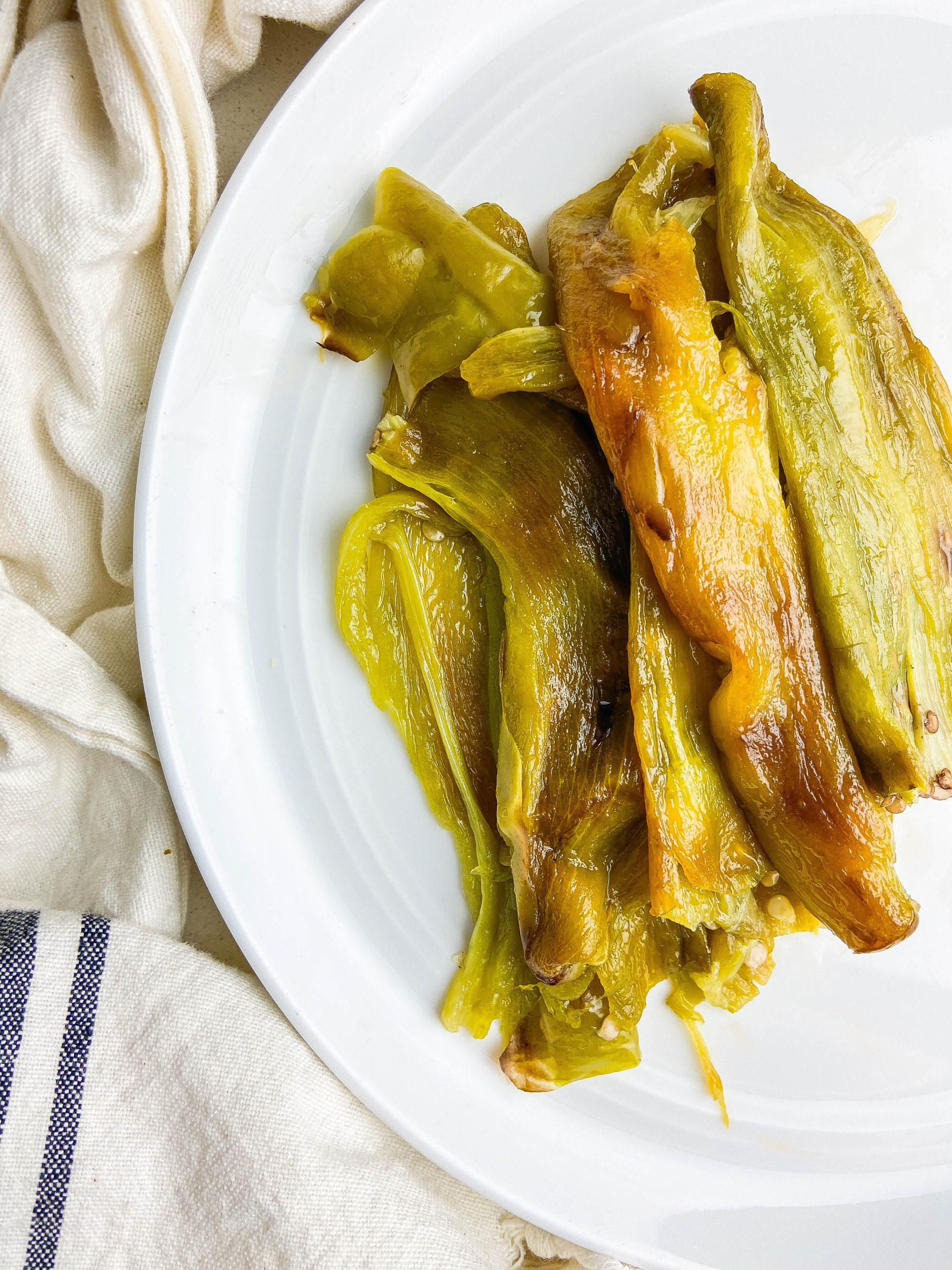 Whole roasted hatch chiles on a white plate. 