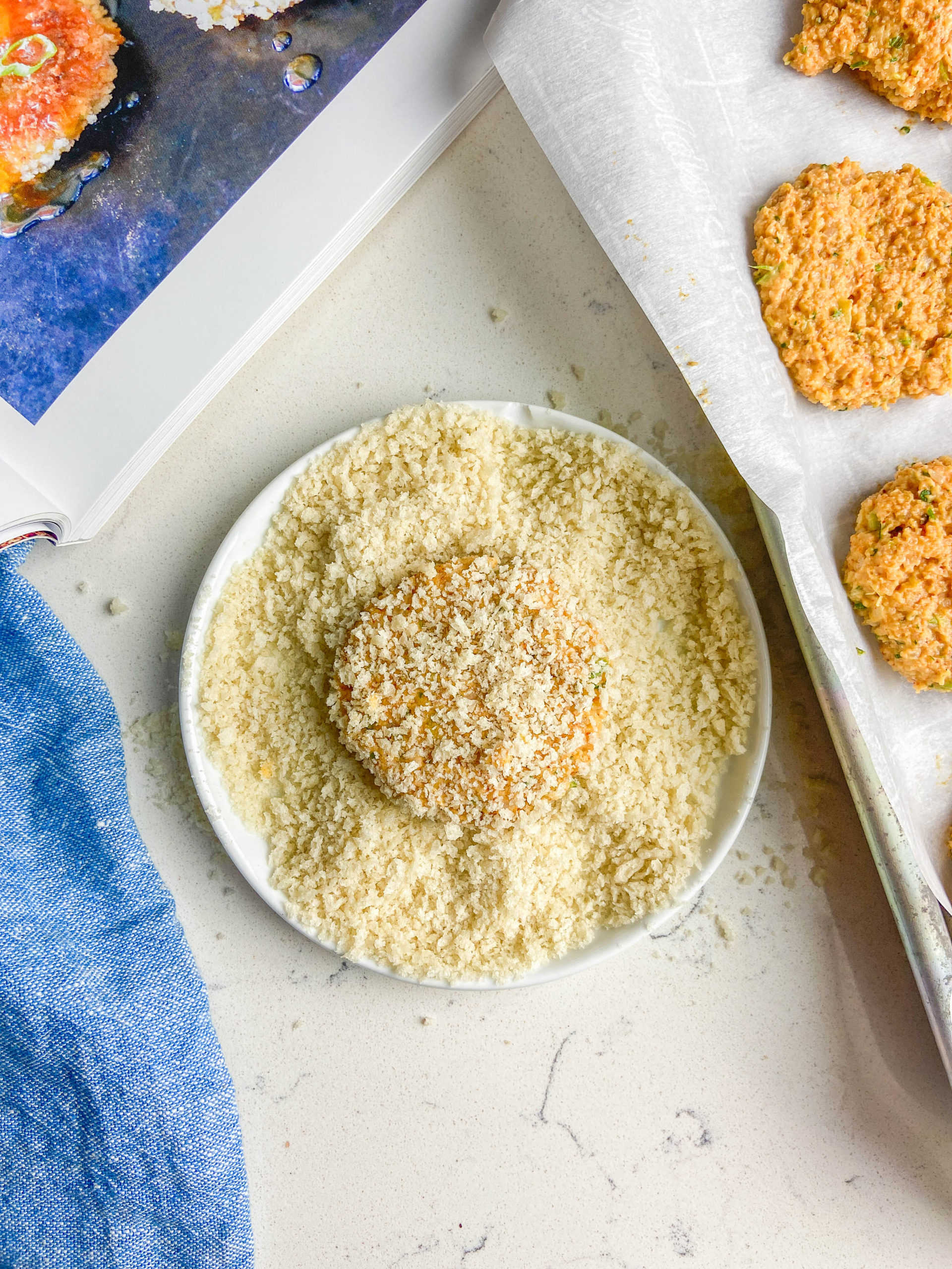 Coated shrimp cake in panko bread crumbs on white plate. 