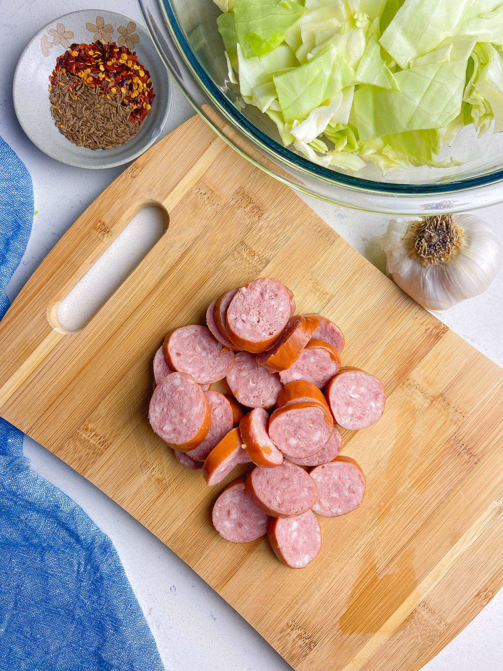 Sliced kielbasa on a wooden cutting board. 