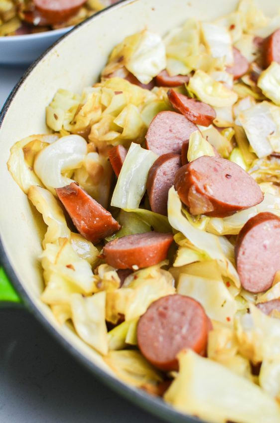 Side angle photo of kielbasa and cabbage in a skillet.