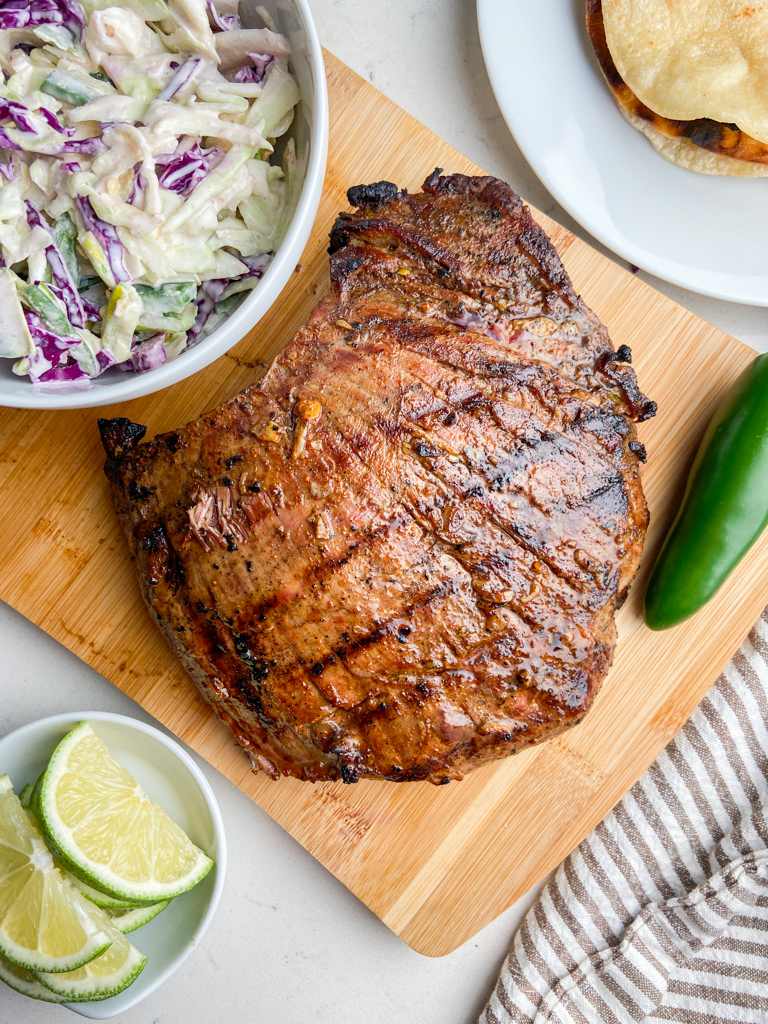 Grilled flank Steak on a cutting board  with coleslaw. 