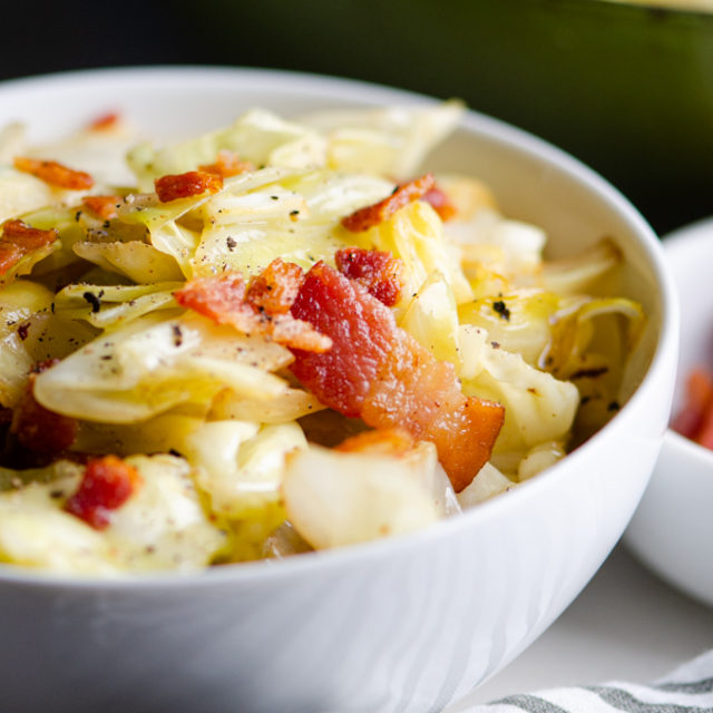 Close up side angle photo of cabbage with bacon in a bowl.