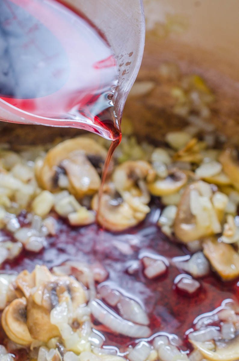 Adding wine to spaghetti sauce. 