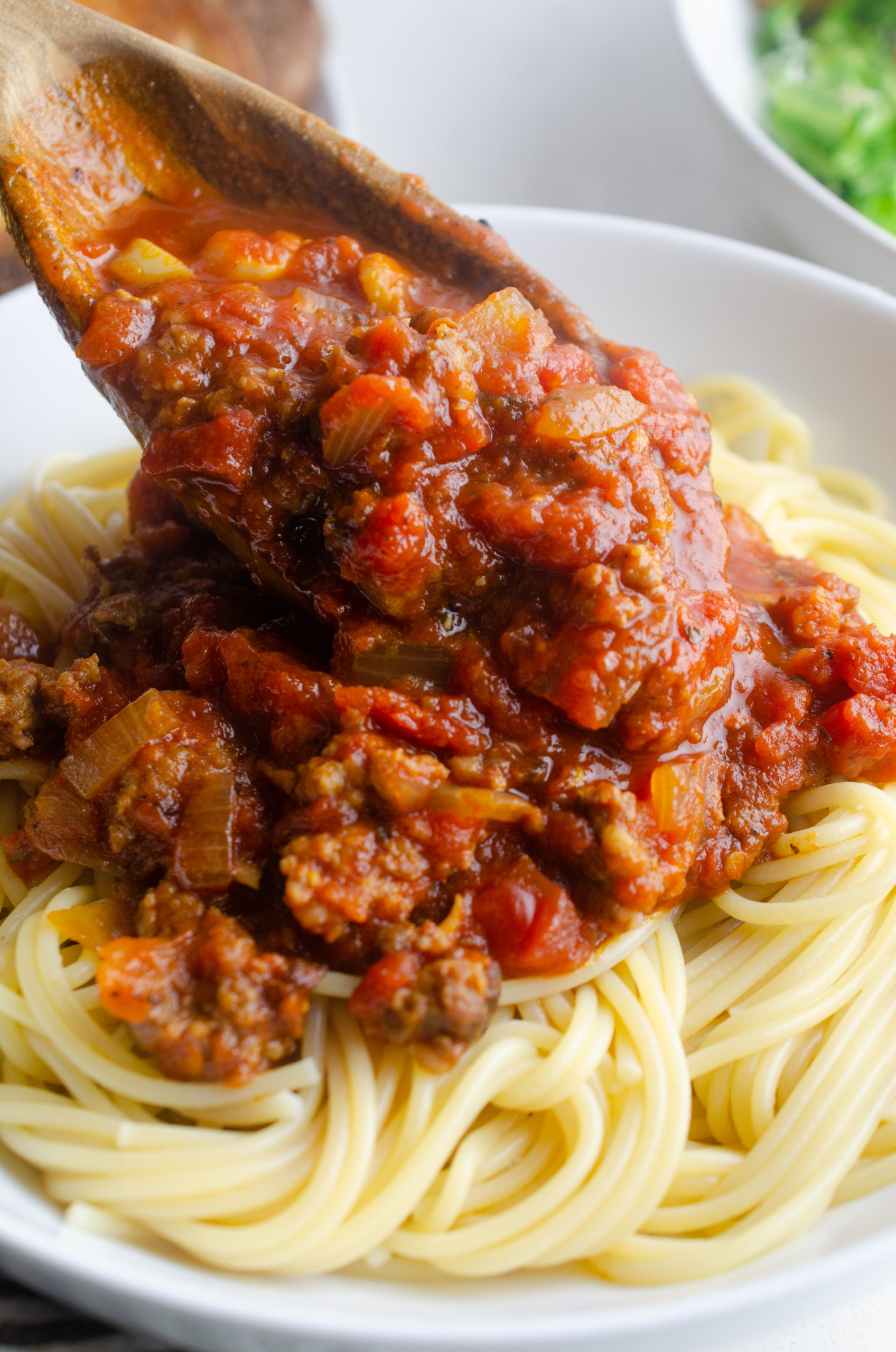 Spooning spaghetti sauce over pasta. 