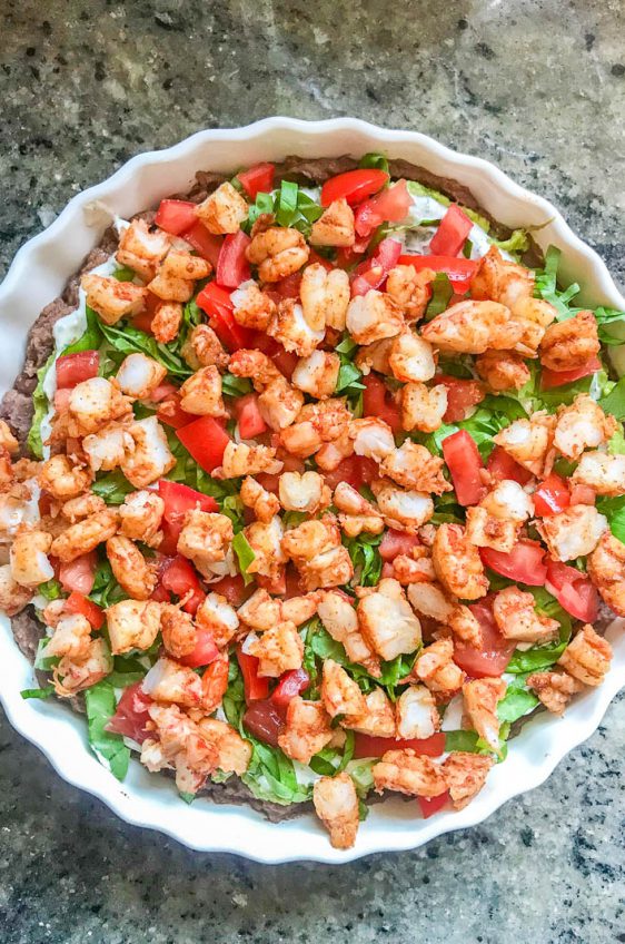 Everyone one loves a good shrimp taco. Everyone loves a good taco dip. I've put them together in this Taco Shrimp Dip with black beans, lettuce, cilantro sour cream, tomatoes and spicy shrimp.