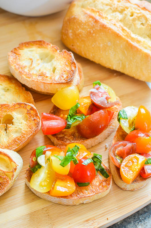 3 pieces of tomato bruschetta on a wooden cutting board.