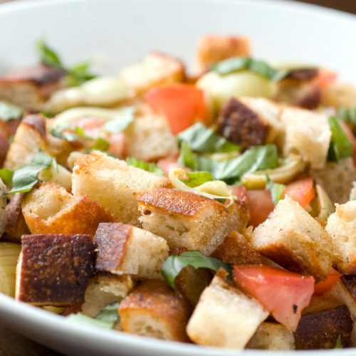 Artichoke Panzanella in a white bowl.