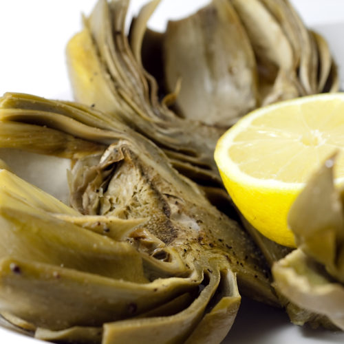 plate of halved baked artichokes with lemon.