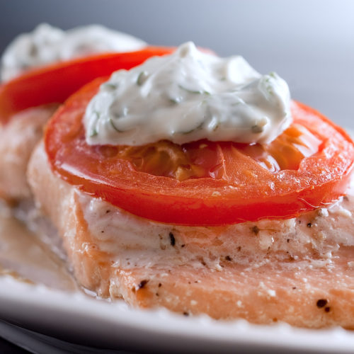 Salmon topped with tomato and basil mayonnaise on plate.