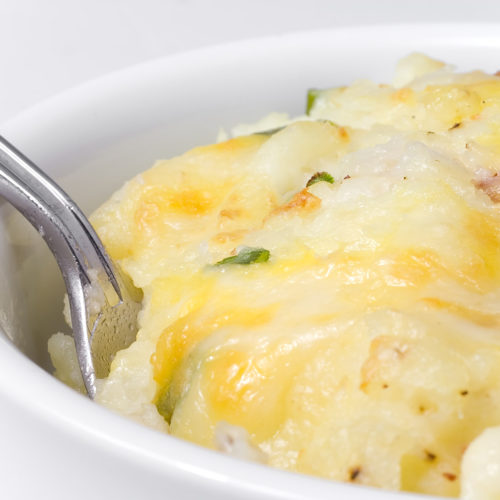 close up of cheesy baked mashed potatoes in dish.