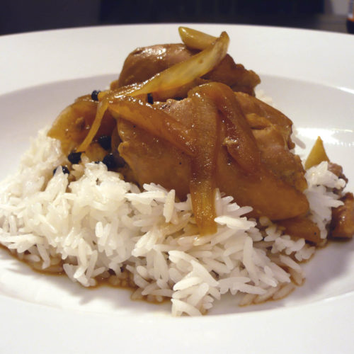 Chicken adobo in white bowl.