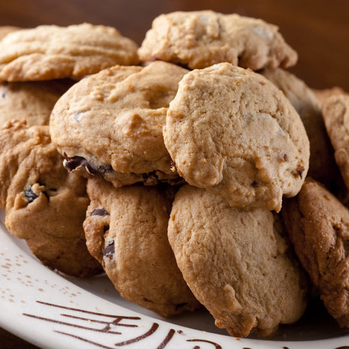 Pile of dark chocolate cherry cookies on plate.