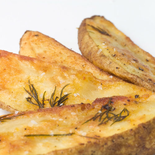 Dill potato wedges on white plate.