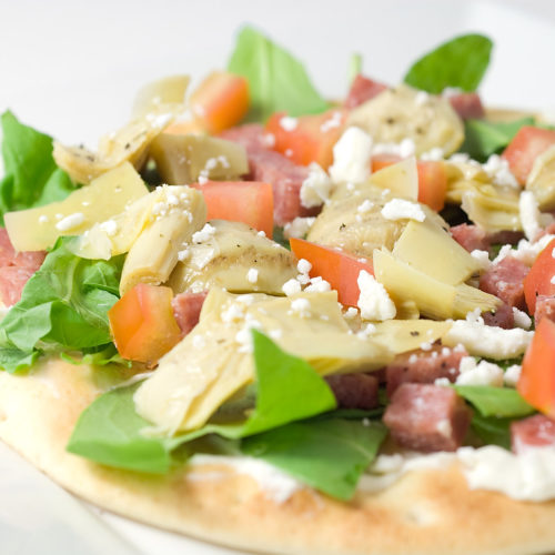 Flat bread pizza on white plate.